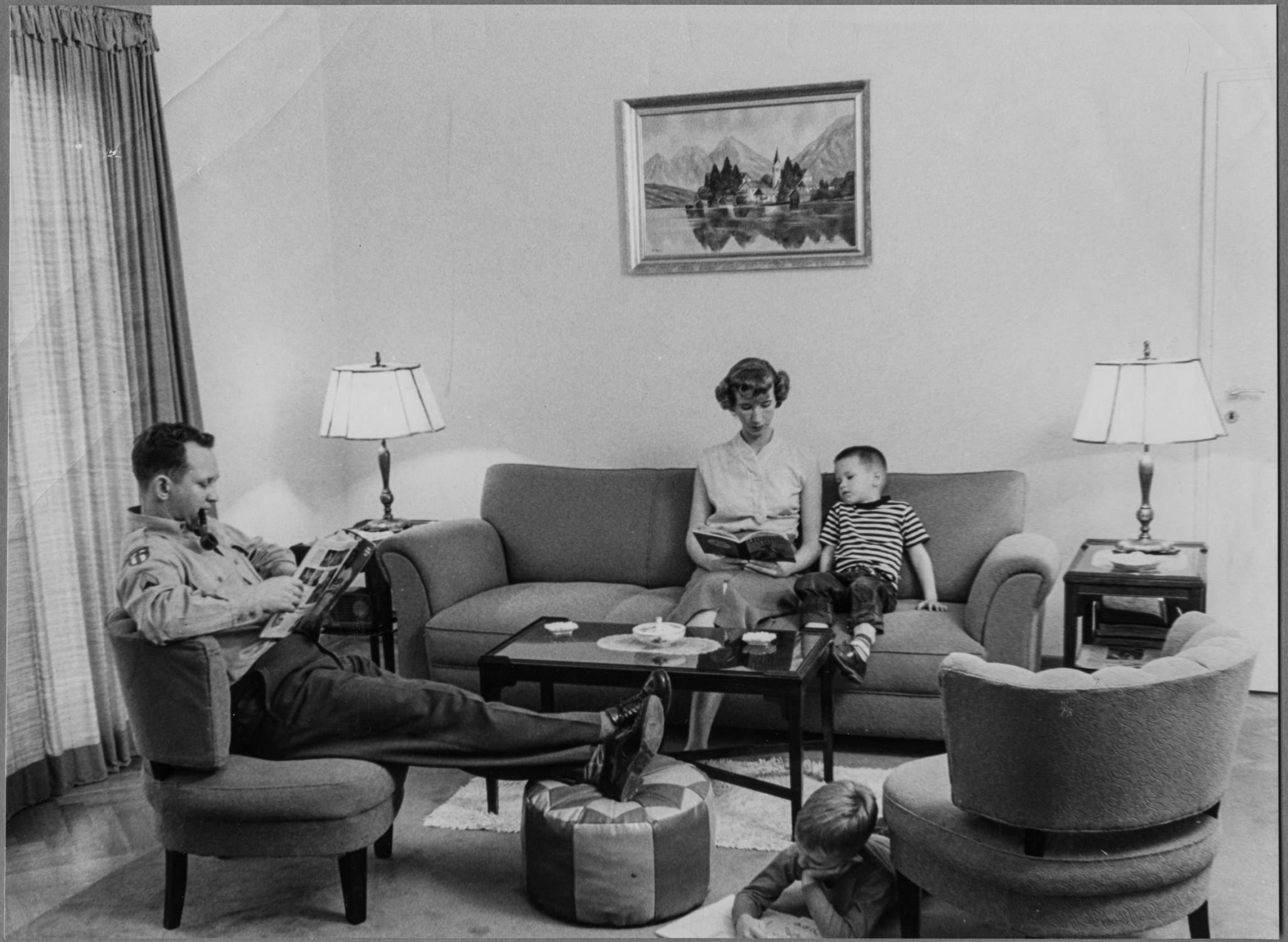 Ein Wohnzimmer in den 50er Jahren. Eine Familie entspannt. Der Vater liest Zeitung, die Mutter zeigt dem Sohn ein Bilderbuch. (Foto: Stadt Heidelberg)